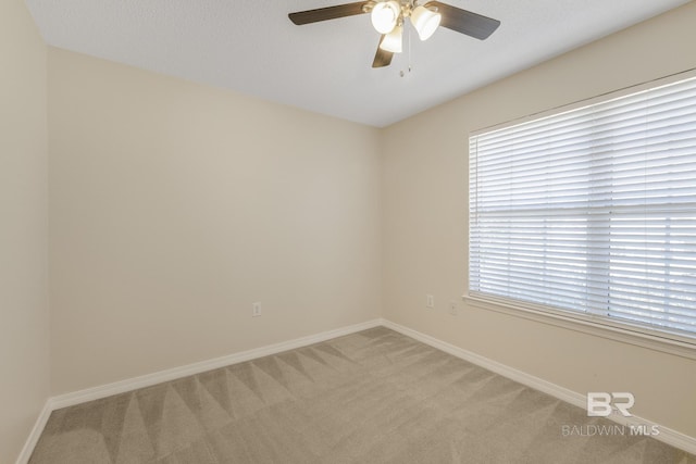 carpeted spare room with ceiling fan and baseboards