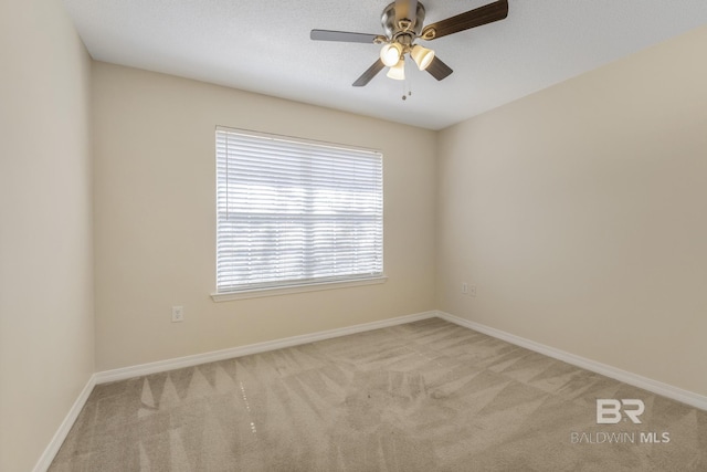 empty room featuring light carpet, ceiling fan, and baseboards