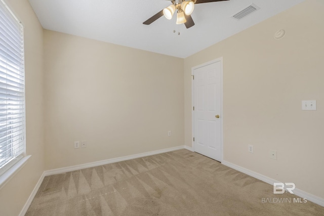 unfurnished room featuring light carpet, a ceiling fan, visible vents, and baseboards