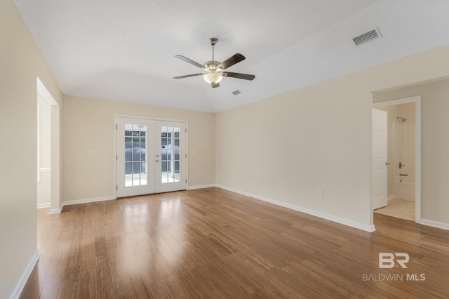 empty room with ceiling fan, wood finished floors, visible vents, baseboards, and french doors