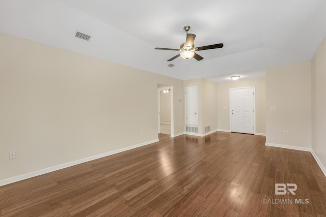 unfurnished room with dark wood-style floors, visible vents, baseboards, and a ceiling fan