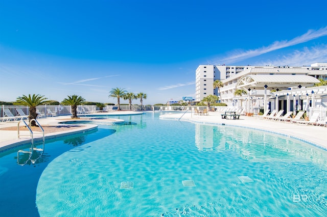 view of swimming pool featuring a hot tub and a patio area