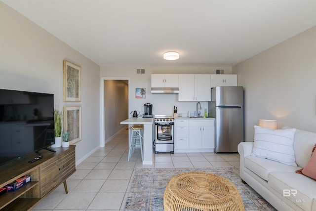 kitchen featuring light tile patterned floors, sink, a breakfast bar area, white cabinetry, and stainless steel appliances