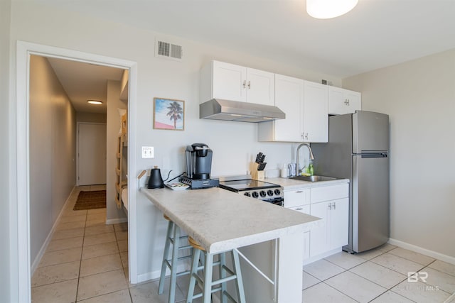 kitchen with light tile patterned floors, sink, stainless steel appliances, white cabinets, and a kitchen bar