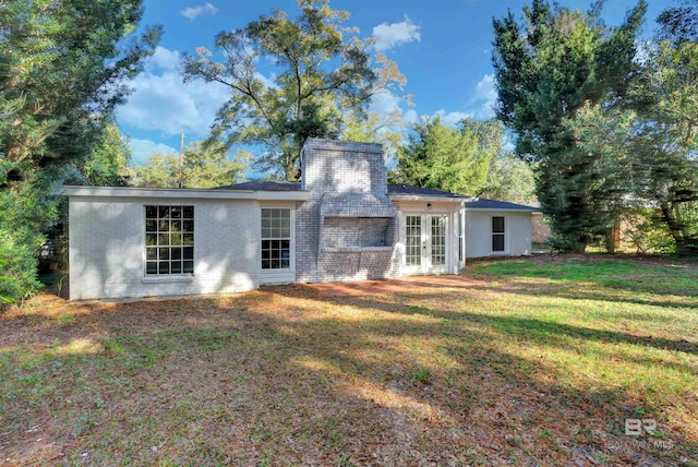 rear view of house with french doors and a lawn