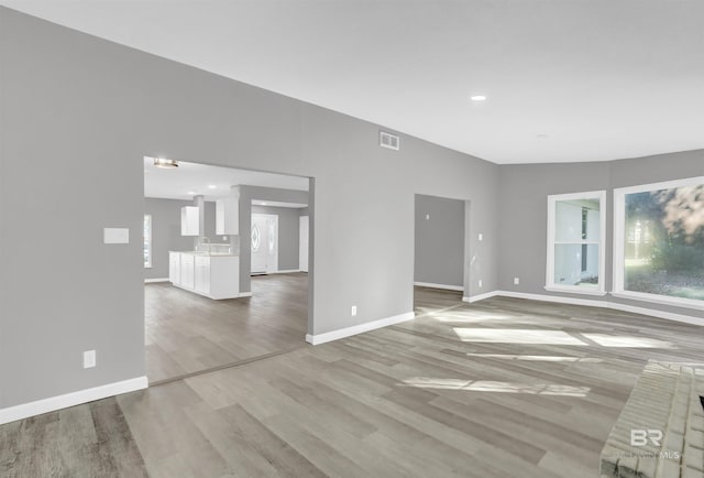 spare room featuring light hardwood / wood-style floors and vaulted ceiling