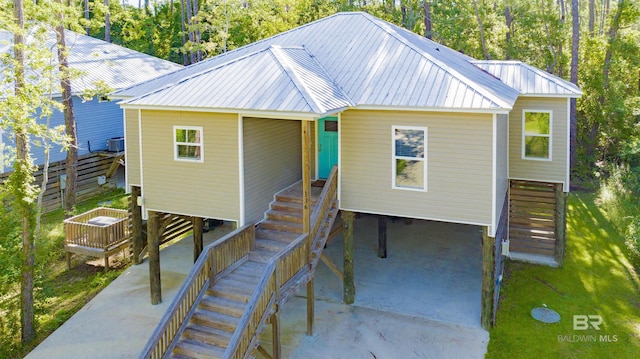 beach home featuring stairway, central AC, concrete driveway, and metal roof