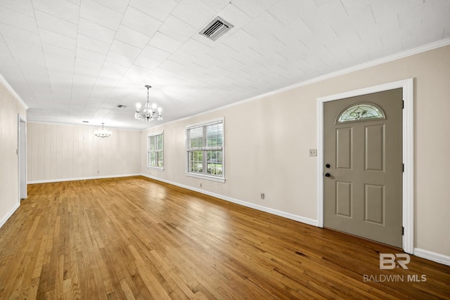 entrance foyer with wood-type flooring, ornamental molding, and a notable chandelier