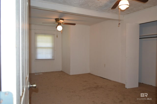 unfurnished bedroom with a closet, a textured ceiling, light colored carpet, and ceiling fan