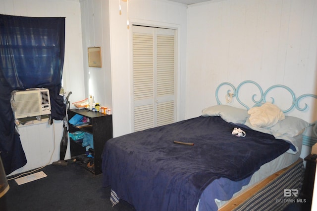 carpeted bedroom with crown molding, wooden walls, and a closet