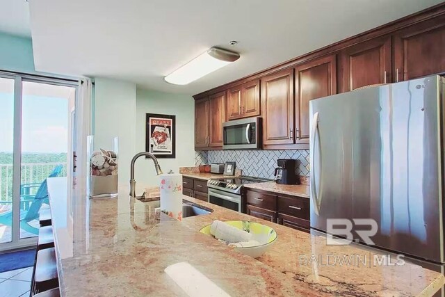 kitchen featuring backsplash, light tile patterned floors, stainless steel appliances, sink, and light stone countertops