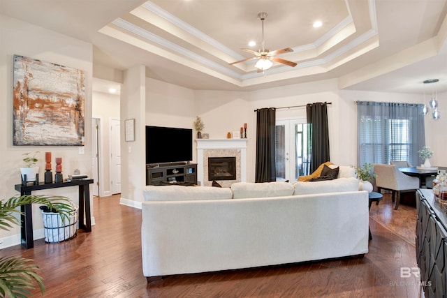 living room with ornamental molding, dark hardwood / wood-style flooring, ceiling fan, and a tray ceiling