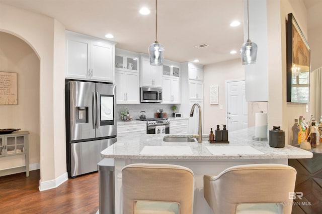 kitchen featuring dark hardwood / wood-style flooring, white cabinetry, hanging light fixtures, and stainless steel appliances