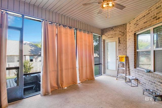 unfurnished sunroom with wood ceiling, a mountain view, and ceiling fan