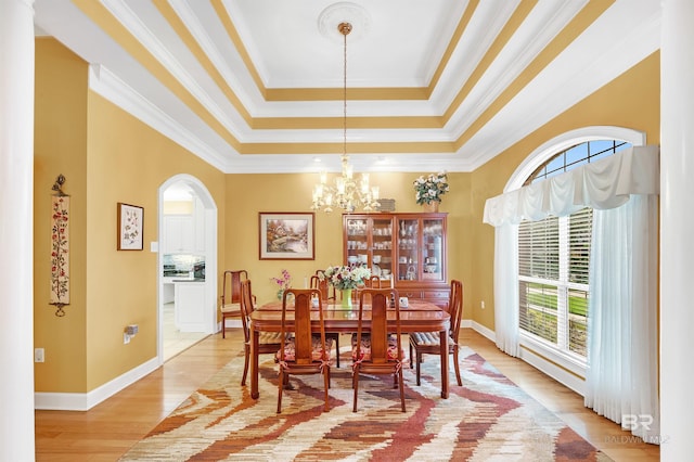 715 Village Dr, Gulf Shores, AL 36542 - dining area featuring arched walkways, a raised ceiling, light wood-style flooring, a chandelier, and ornamental molding