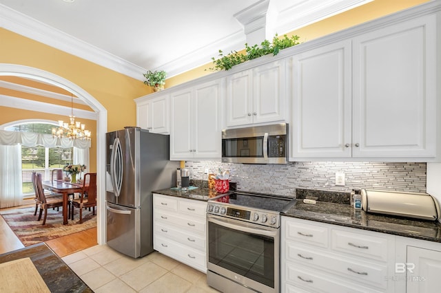 715 Village Dr, Gulf Shores, AL 36542 - kitchen featuring stainless steel appliances, white cabinets, crown molding, dark stone countertops, and decorative backsplash