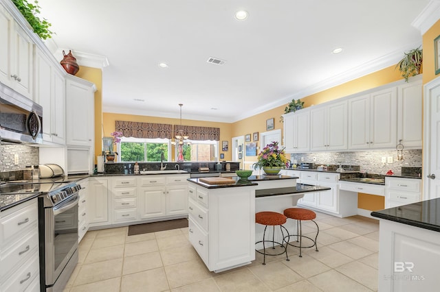 715 Village Dr, Gulf Shores, AL 36542 - kitchen featuring stainless steel appliances, light tile patterned floors, a kitchen breakfast bar, dark countertops, and a kitchen island
