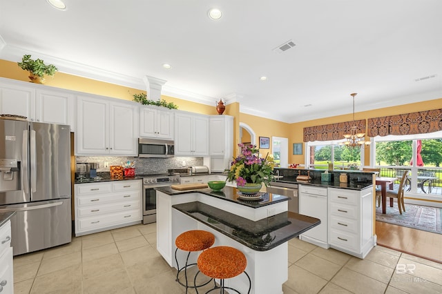 715 Village Dr, Gulf Shores, AL 36542 - kitchen with appliances with stainless steel finishes, a center island, light tile patterned floors, a chandelier, and white cabinetry
