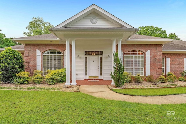 715 Village Dr, Gulf Shores, AL 36542 - view of front of property featuring brick siding, a shingled roof, a front lawn, and a porch