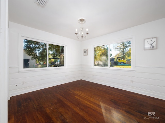 empty room featuring an inviting chandelier and dark hardwood / wood-style floors