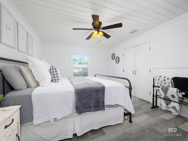 bedroom featuring wood-type flooring, crown molding, ceiling fan, and a closet