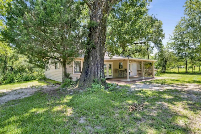 back of property featuring a lawn, french doors, and a patio