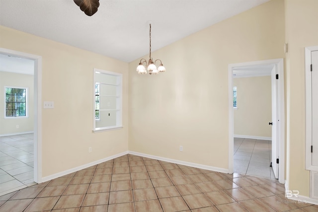 tiled spare room with an inviting chandelier