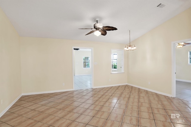 spare room featuring light tile patterned floors and ceiling fan with notable chandelier