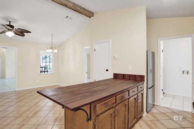 kitchen with lofted ceiling with beams, butcher block countertops, hanging light fixtures, and light tile patterned flooring