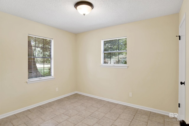 unfurnished room with light tile patterned floors and a textured ceiling