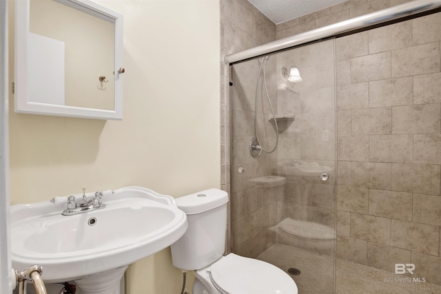 bathroom featuring a textured ceiling, toilet, a shower with shower door, and sink