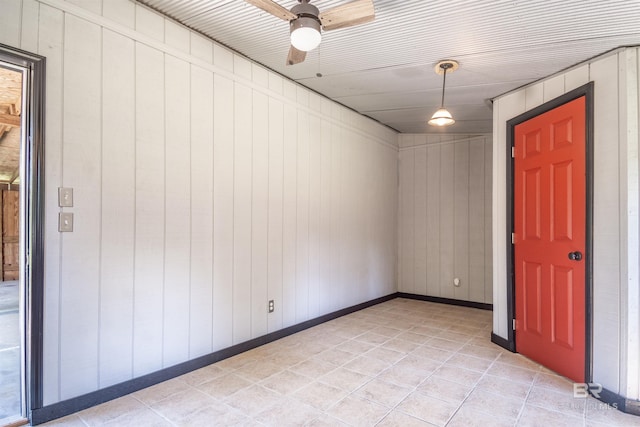 spare room featuring ceiling fan and wood walls