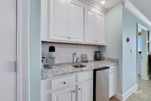 kitchen featuring light tile patterned flooring, sink, light stone counters, white cabinets, and backsplash