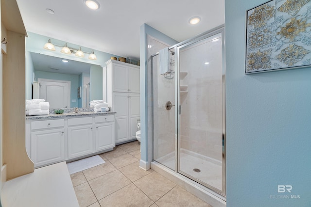 bathroom featuring vanity, toilet, tile patterned floors, and a shower with shower door