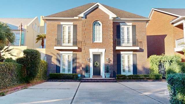 view of front facade featuring brick siding and a balcony