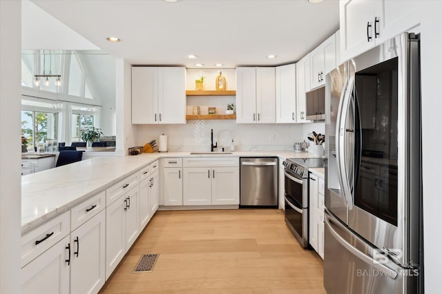 kitchen featuring light stone countertops, appliances with stainless steel finishes, sink, light hardwood / wood-style floors, and white cabinetry