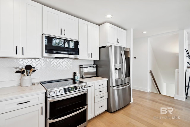 kitchen with light hardwood / wood-style flooring, decorative backsplash, light stone countertops, appliances with stainless steel finishes, and white cabinetry