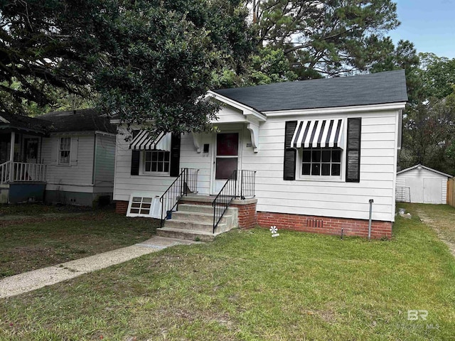 bungalow featuring a storage shed and a front lawn