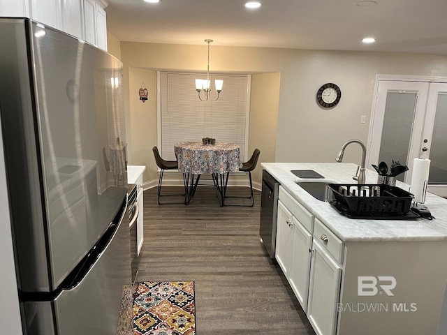 kitchen with sink, white cabinets, hanging light fixtures, stainless steel appliances, and a center island with sink