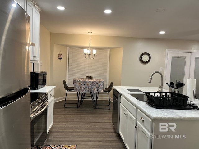 kitchen featuring decorative light fixtures, sink, white cabinets, dark hardwood / wood-style flooring, and stainless steel appliances