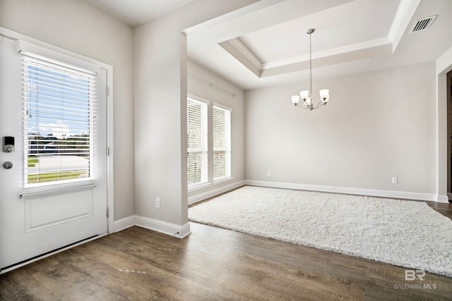 interior space featuring dark wood-type flooring, a chandelier, ornamental molding, and a tray ceiling