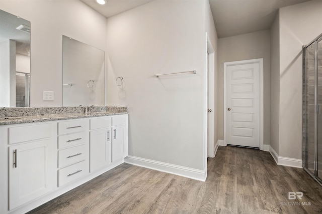 bathroom with hardwood / wood-style floors, vanity, and an enclosed shower