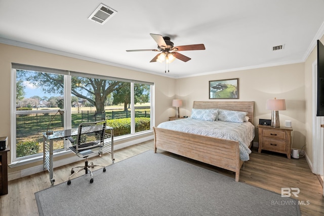 bedroom with ornamental molding, wood finished floors, visible vents, and baseboards