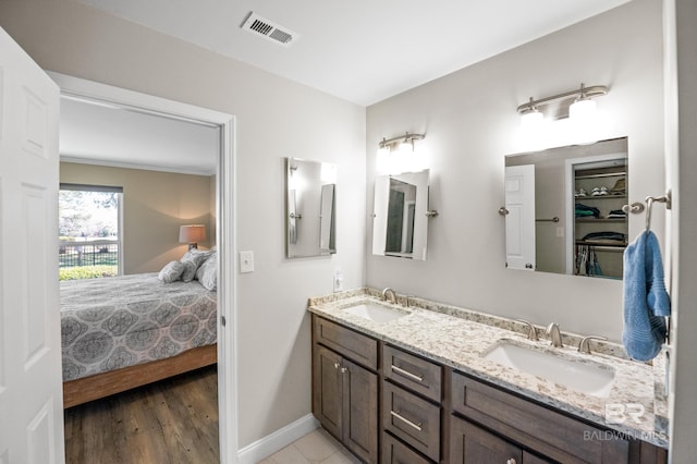 bathroom with baseboards, ensuite bath, visible vents, and a sink