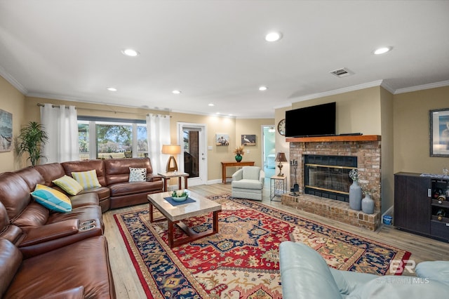 living room featuring visible vents, ornamental molding, wood finished floors, a brick fireplace, and recessed lighting