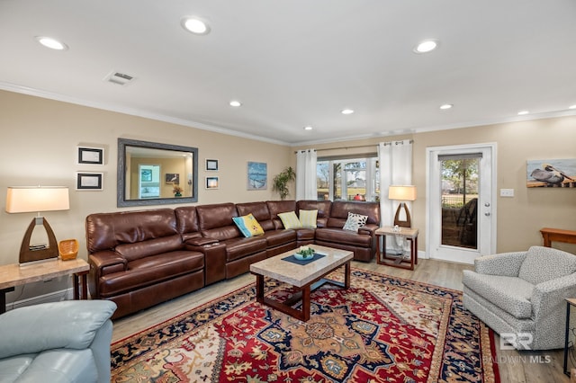 living area featuring ornamental molding, visible vents, and wood finished floors