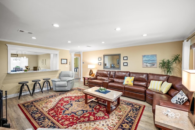 living room featuring recessed lighting, wood finished floors, visible vents, ornamental molding, and decorative columns