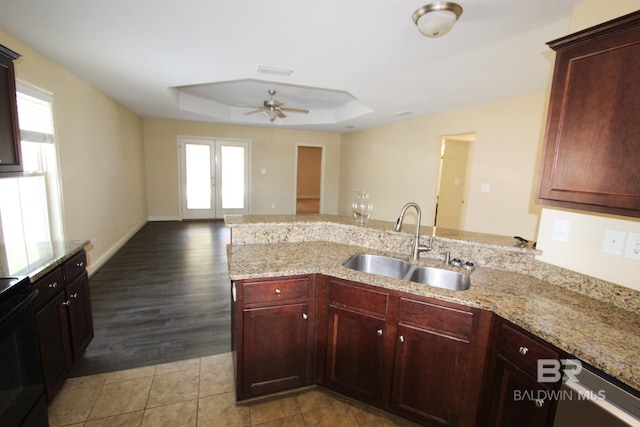 kitchen featuring sink, light stone counters, a tray ceiling, black electric range, and french doors