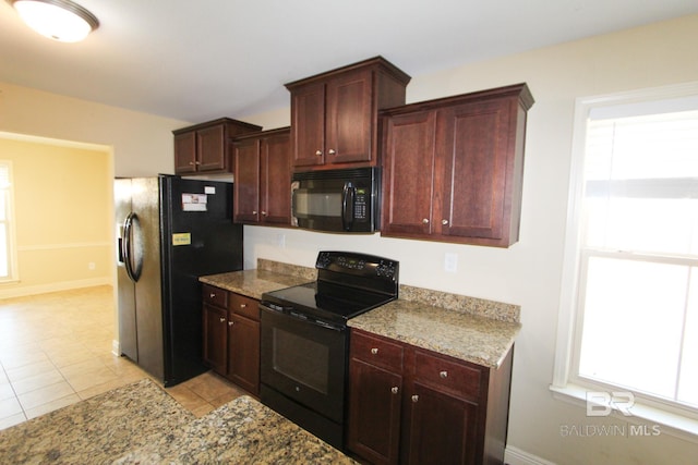 kitchen with light stone countertops, light tile patterned floors, and black appliances