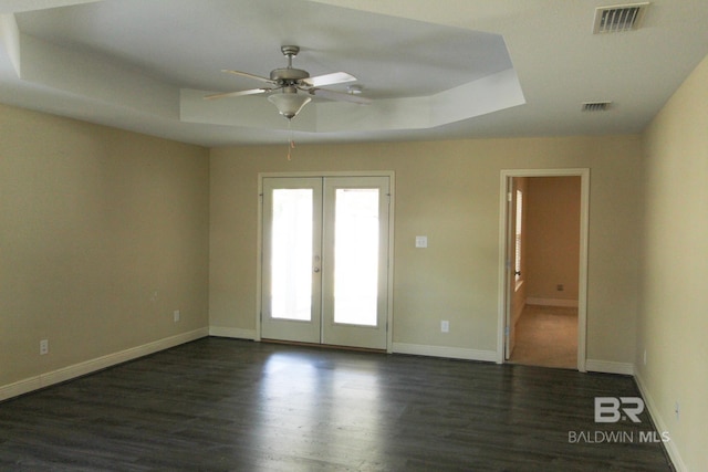 spare room featuring a raised ceiling, dark hardwood / wood-style floors, ceiling fan, and french doors